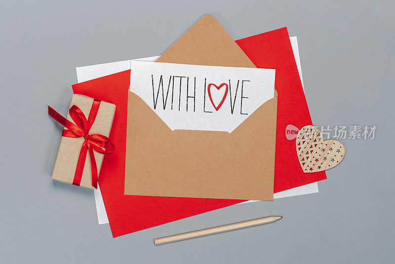 Falt lay组成的工艺纸信封和白色卡片与手写的情人节问候，孤立的灰色背景